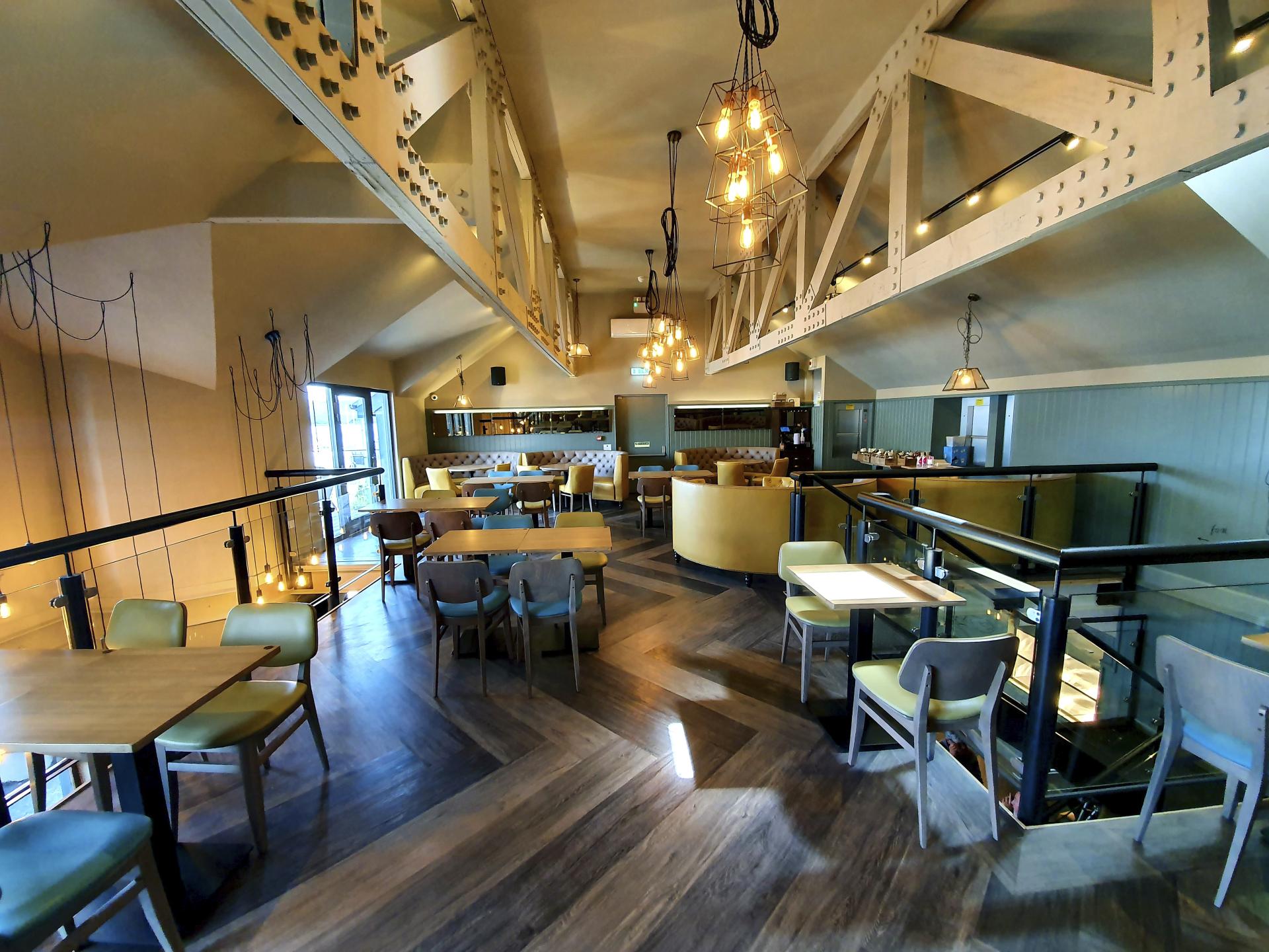 Stylish restaurant interior featuring wooden floors, modern lighting, and flexible seating arrangements for a welcoming dining experience.