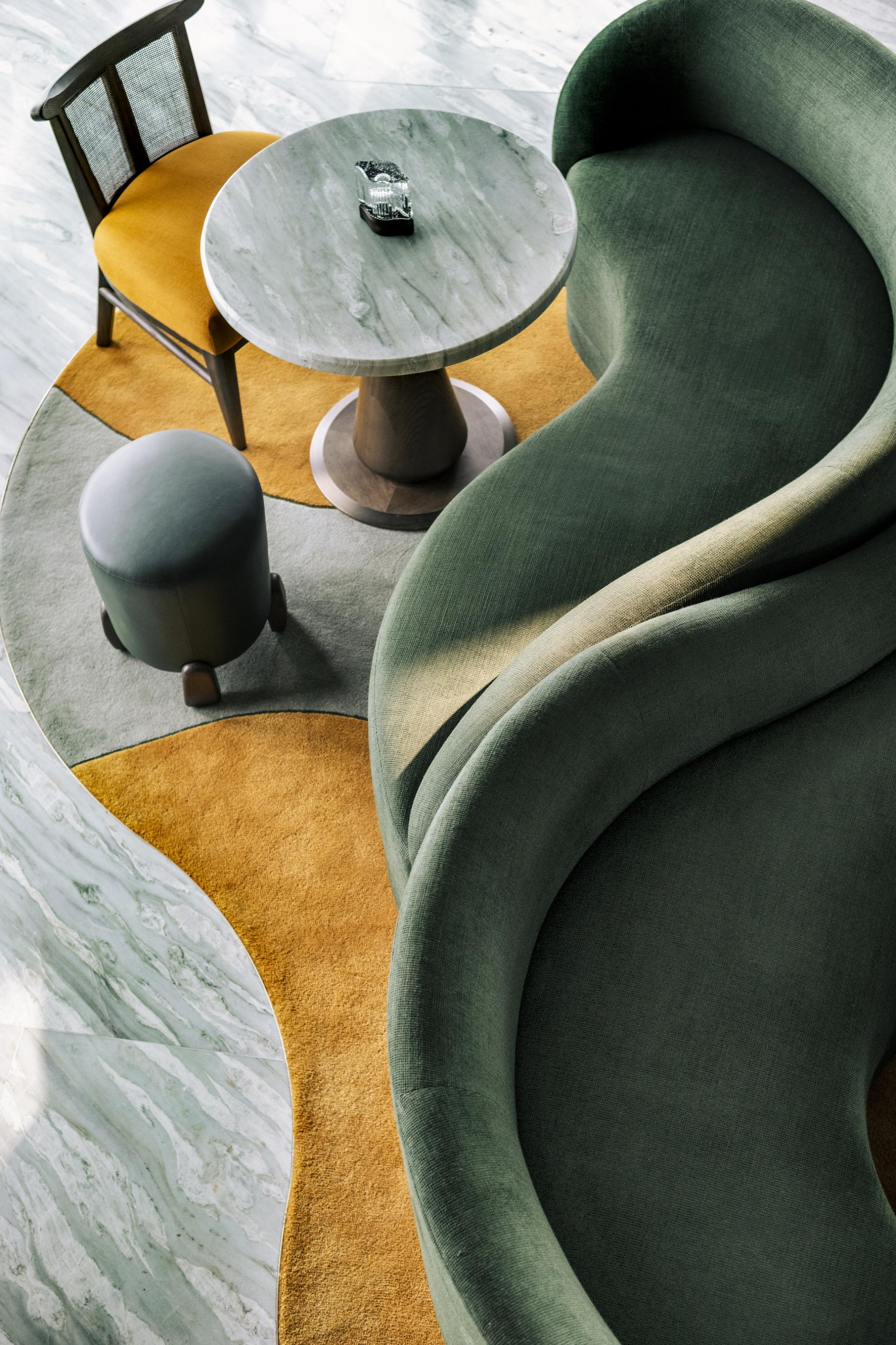 Stylish Art Deco seating with a round marble table, set on a colorful area rug in The Upper House, Hong Kong.