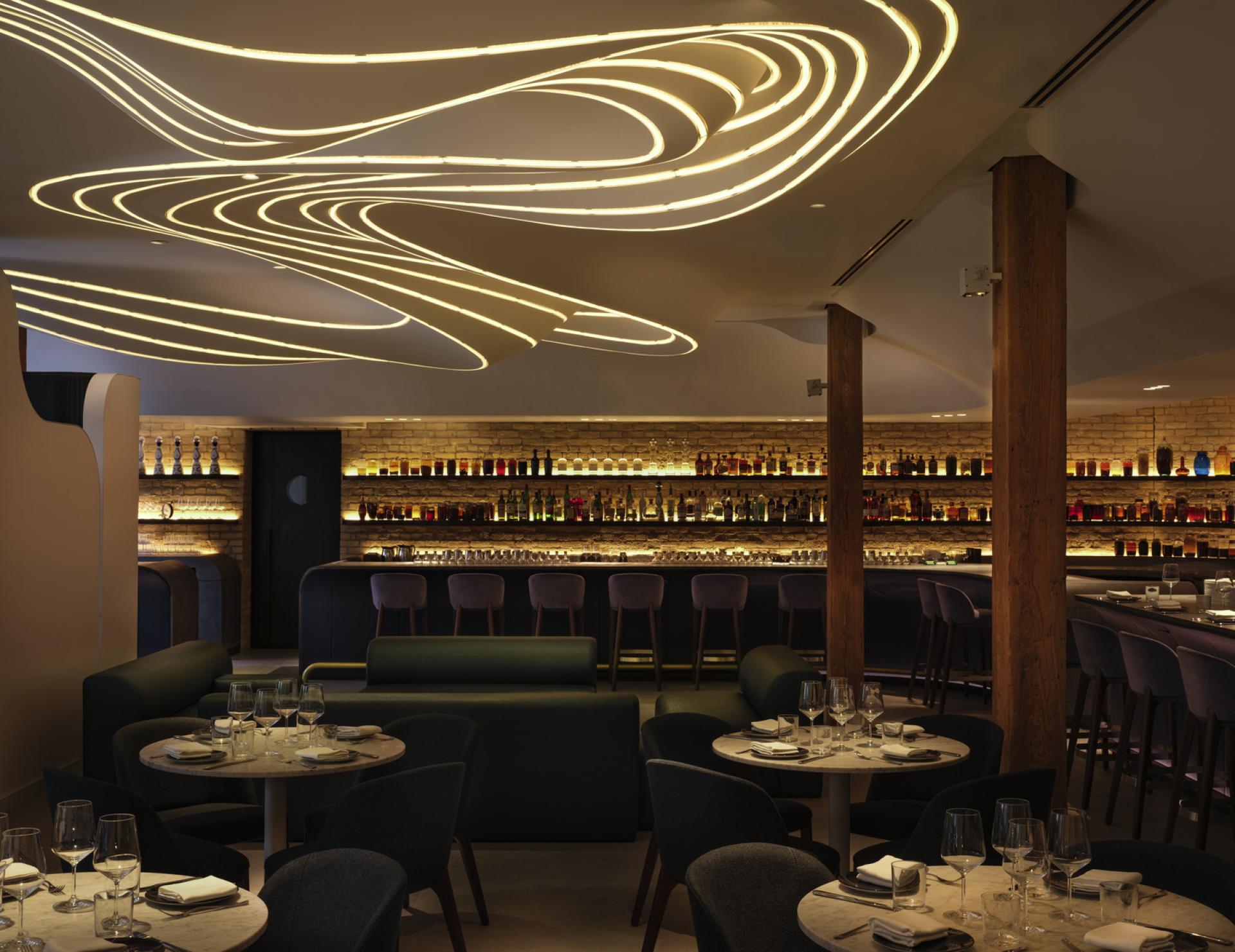 Sophisticated interior of VELA restaurant featuring ambient lighting and a stylish bar, inspired by constellations.