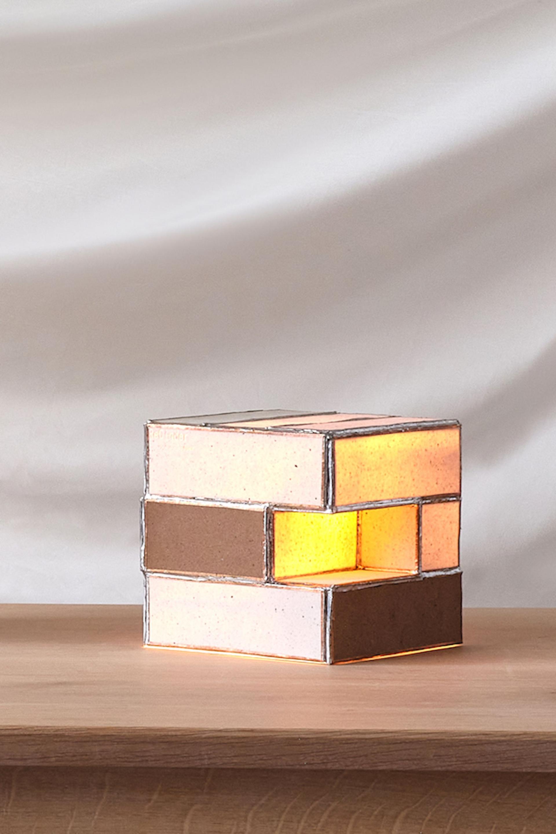 Sustainable designer lamp showcasing innovative materiality, featuring warm light and a modern geometric design on a wooden table.