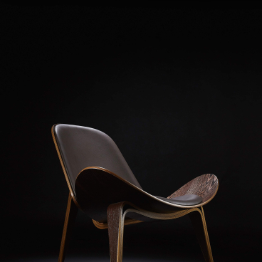 Elegant modern chair with wooden frame and leather seating, showcasing exclusive design at the London Design Festival.