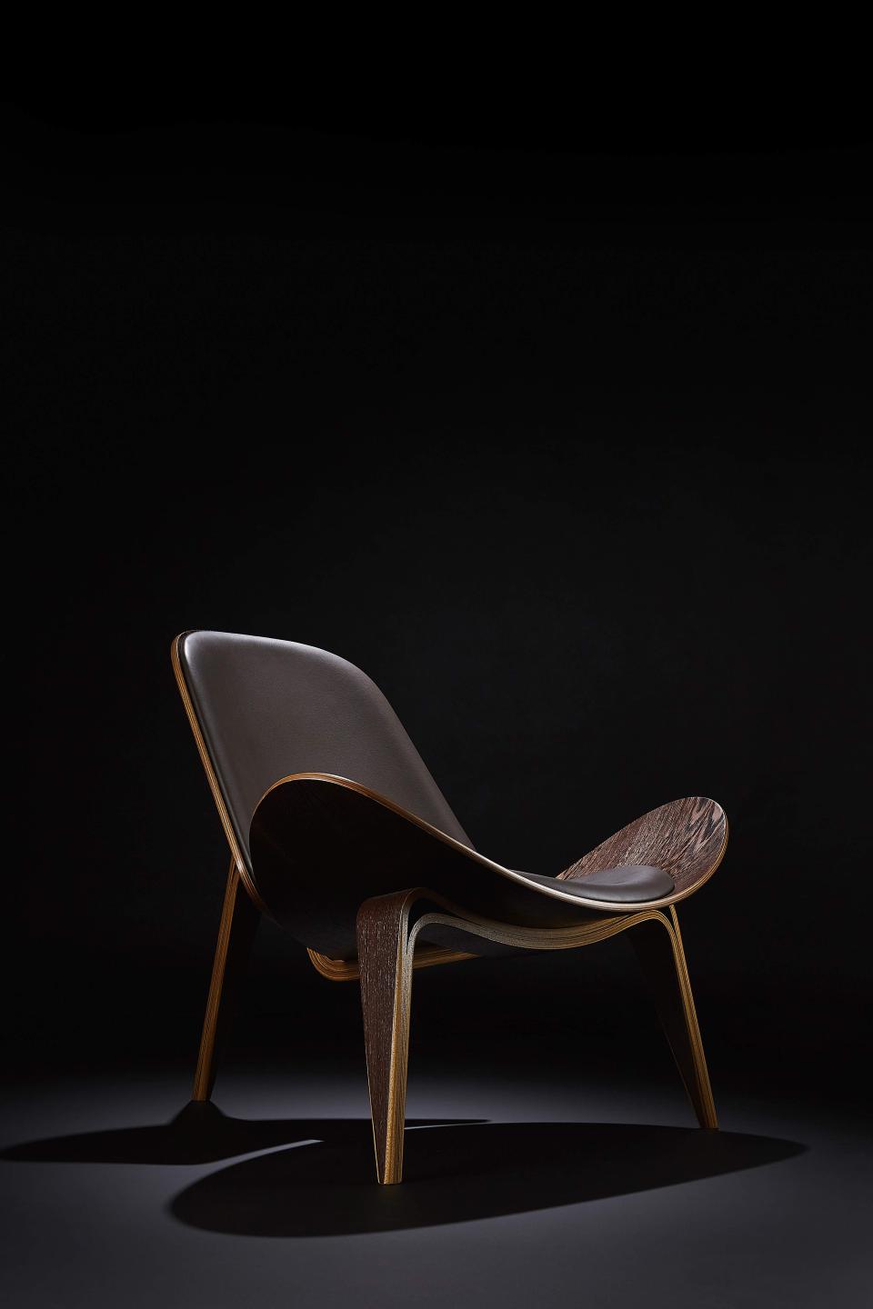 Elegant modern chair with wooden frame and leather seating, showcasing exclusive design at the London Design Festival.