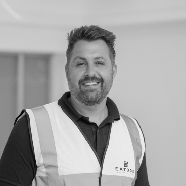 Smiling man in a safety vest representing Eatock Design & Build, symbolizing resilience in business during lockdown.