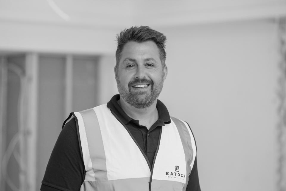 Smiling man in a safety vest representing Eatock Design & Build, symbolizing resilience in business during lockdown.