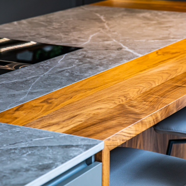 Stylish kitchen countertop with contrasting grey Dekton surface and warm wooden accents, designed for multifunctional living.