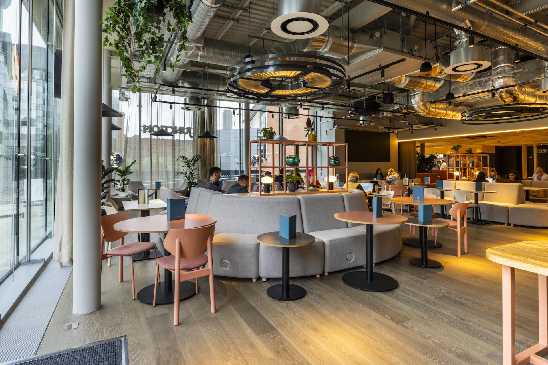 Modern café interior at Junction, Manchester Central, showcasing collaborative design elements and inviting social spaces.