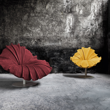 Vibrant Kenneth Cobonpue floral-inspired chairs in red and yellow, set against a textured gray backdrop, celebrating spring's essence.