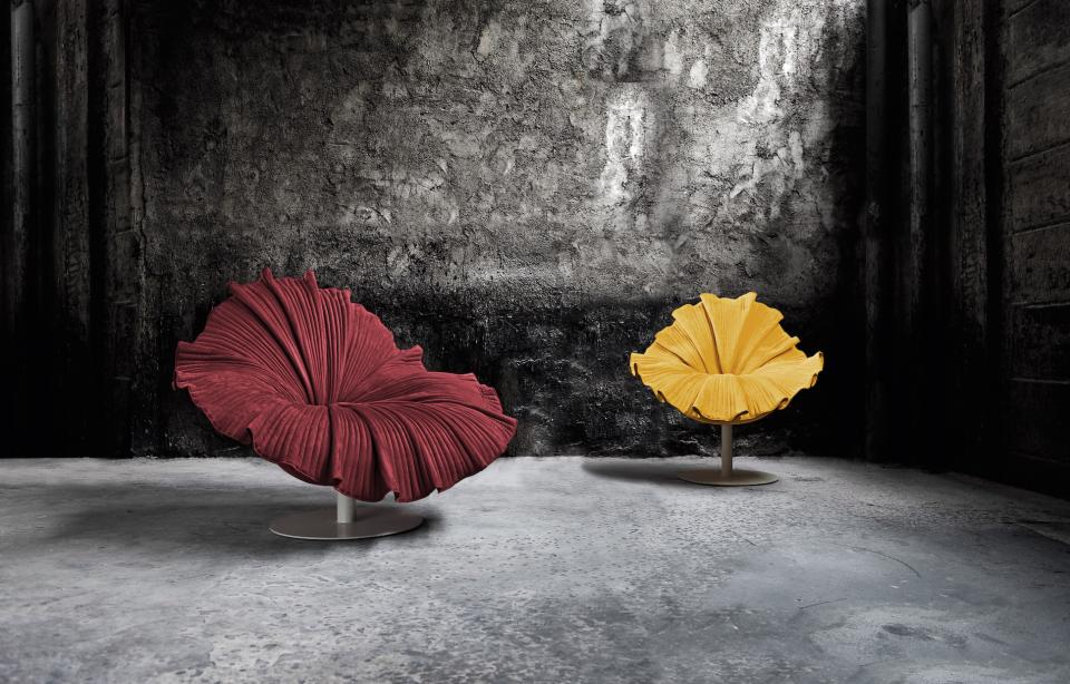 Vibrant Kenneth Cobonpue floral-inspired chairs in red and yellow, set against a textured gray backdrop, celebrating spring's essence.