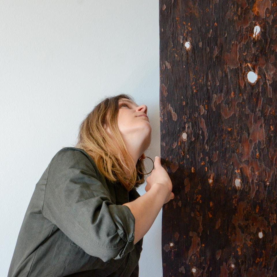 Latvian designer examining a textured biomaterial panel, showcasing Studio Sarmite's innovation in sustainable design and waste reimagining.