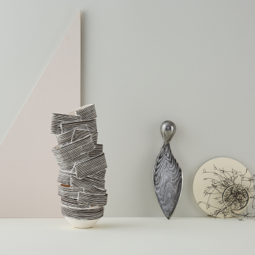 Artistic display features a stacked ceramic vase, elegant sculpture, and abstract wire design, highlighting innovative design talent.
