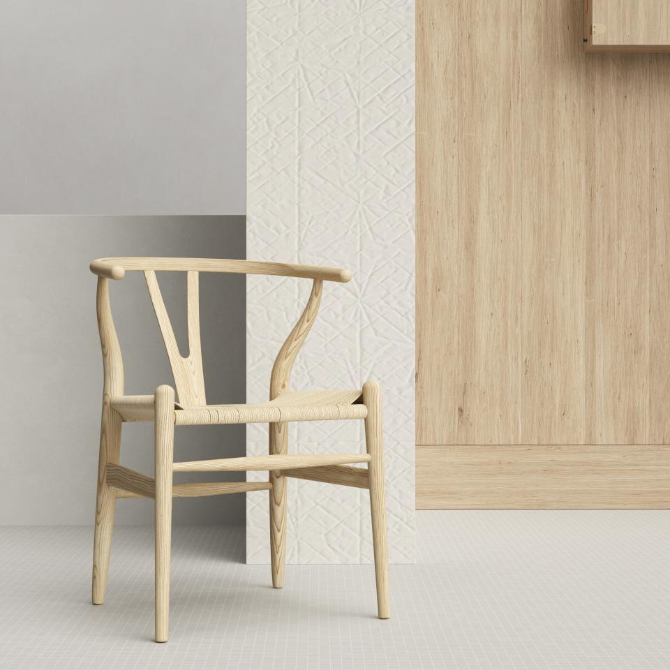 Stylish wooden chair positioned beside textured ceramic tiles and wood paneling, showcasing Mutina's design collaboration with OEO Studio.