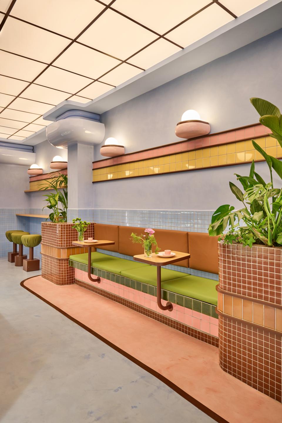 Colorful interior of a Barcelona ice cream parlour, featuring Art Deco-inspired design with decorative tiles and lush greenery.
