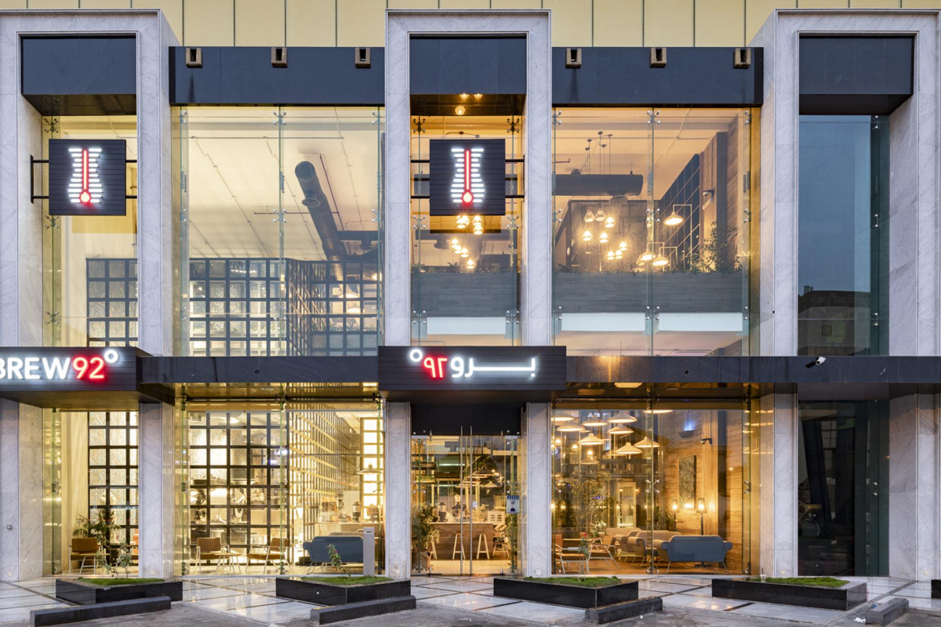 Modern facade of Brew92 cafe in Saudi Arabia, showcasing sleek glass design, inviting interior, and distinctive branding.