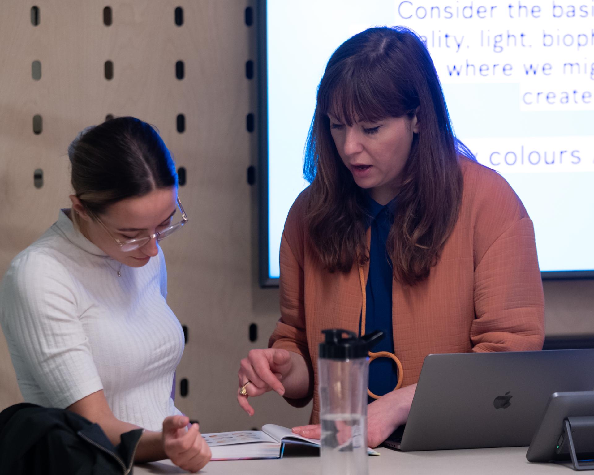 Laura Perryman guides a student through a colour theory workshop, emphasizing biophilia and nature's aesthetic imperfections.