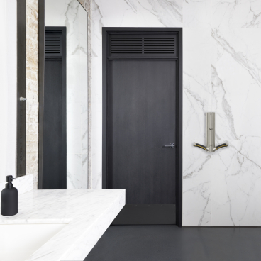 Modern bathroom featuring a sleek marble wall, minimalist sink, and a stylish Dyson hand dryer, emphasizing sustainable design.