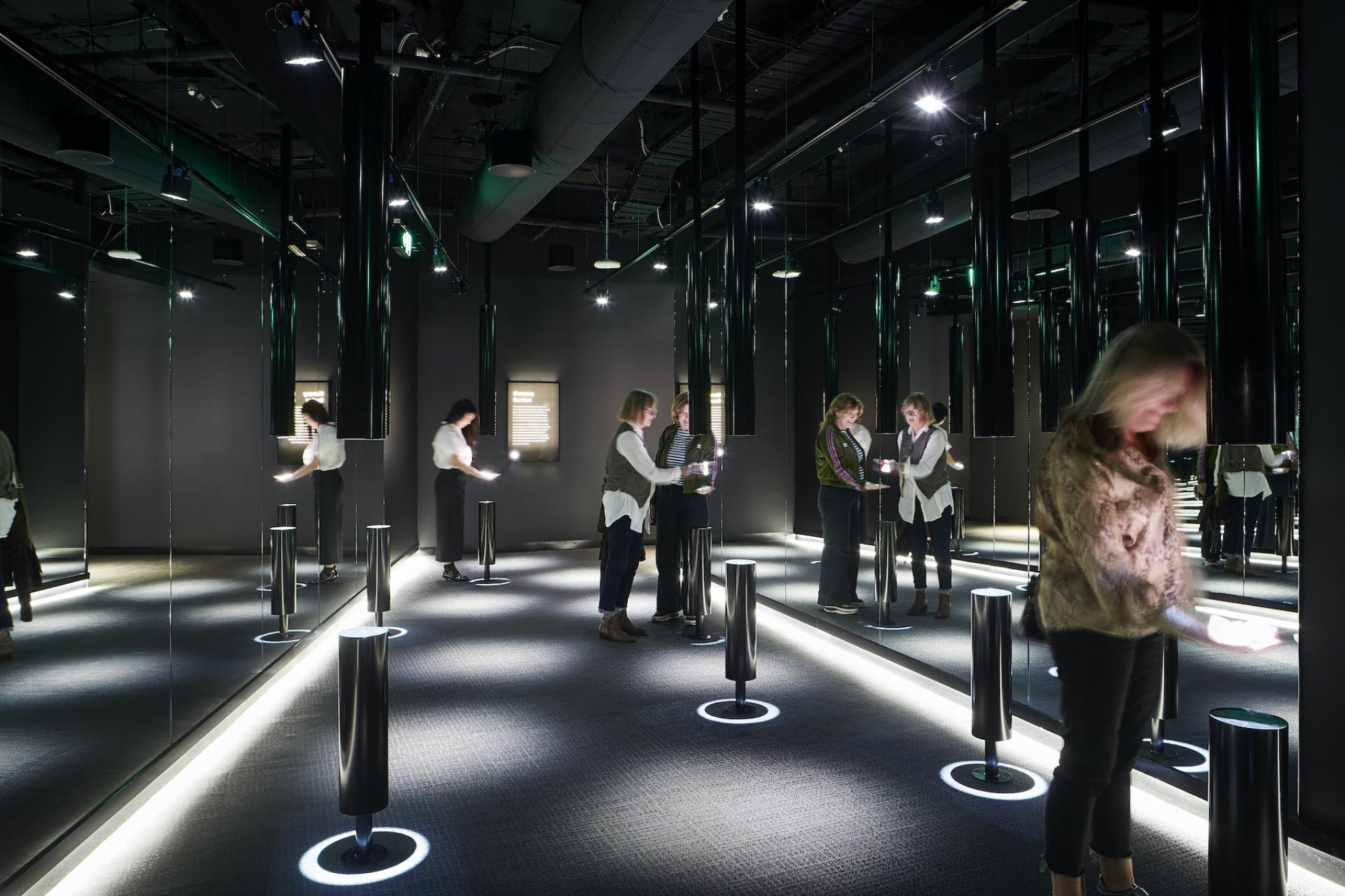 Visitors exploring an interactive exhibit in the newly reimagined ACMI museum, featuring innovative lighting and reflective surfaces.