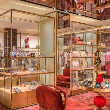 Elegant interior of Dolce & Gabbana's Venetian store featuring luxurious displays, vibrant fashions, and opulent seating.