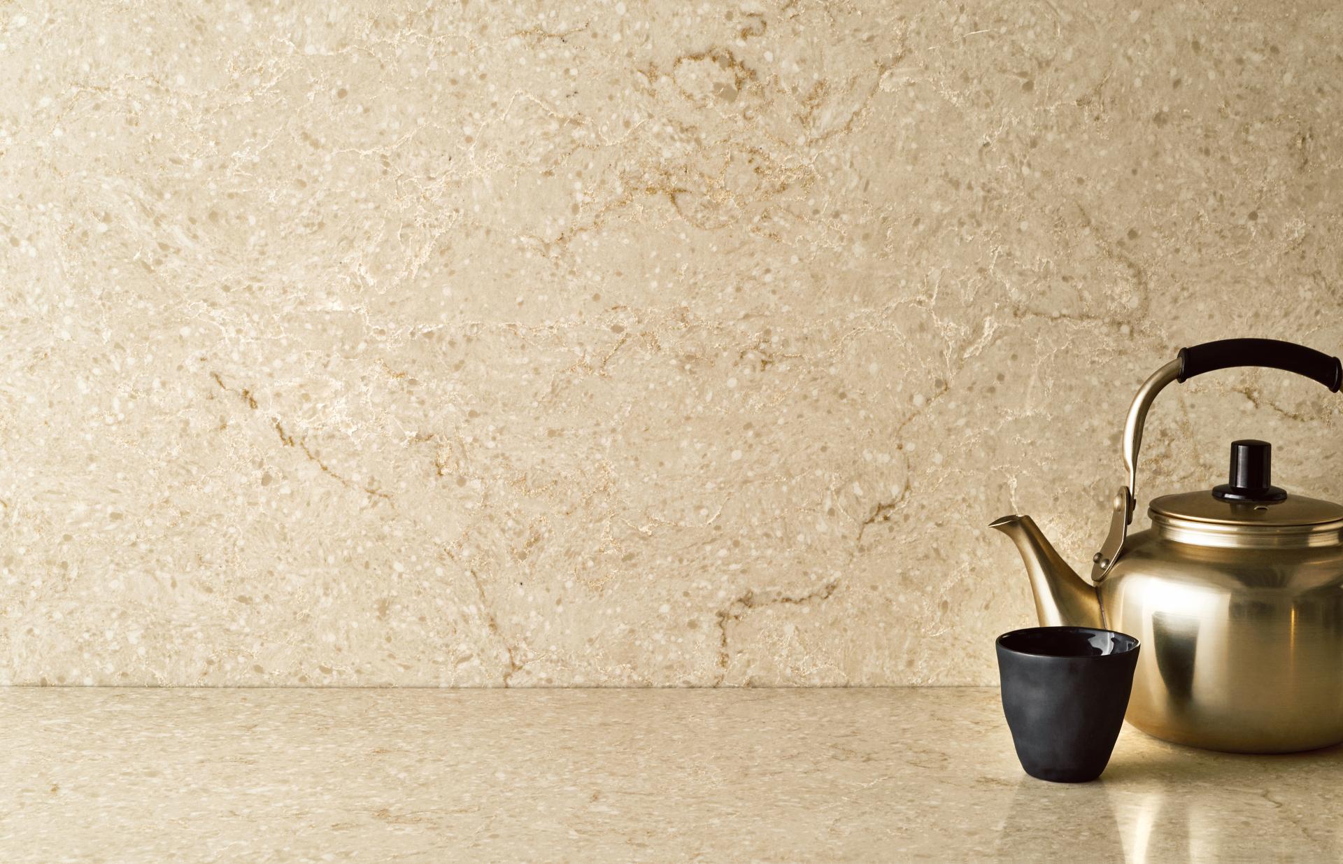 Taj Royale countertop showcasing warm beige tones with dark brown veins, accompanied by a metallic kettle and black cup.