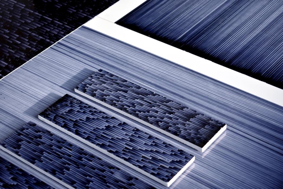 Textured ceramic tiles in varying shades of blue, showcasing Léa Mazy's innovative printing techniques for the tile industry.