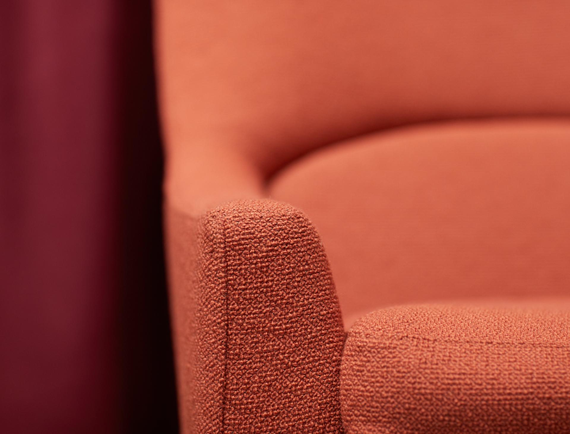 Close-up of an orange upholstered armchair showcasing Camira's advanced textile treatment for enhanced safety and durability.