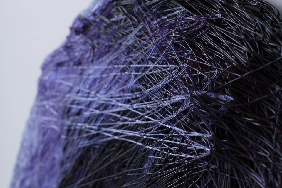 Close-up view of Nuatan, a biodegradable bioplastic, showcasing its unique, intertwining strands in shades of black and purple.