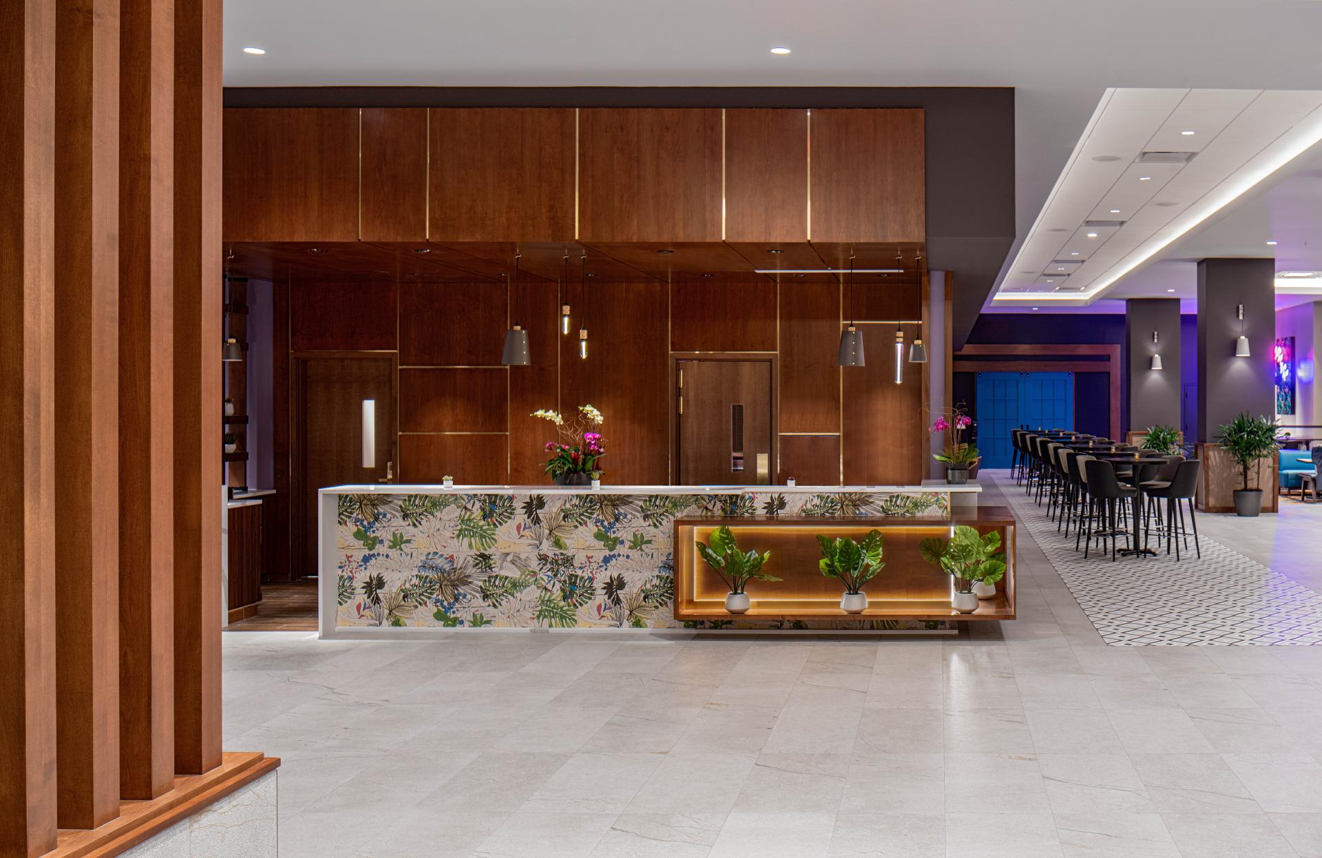 Modern lobby design at Hyatt House Tampa featuring vibrant floral patterns, elegant wood finishes, and stylish lighting elements.