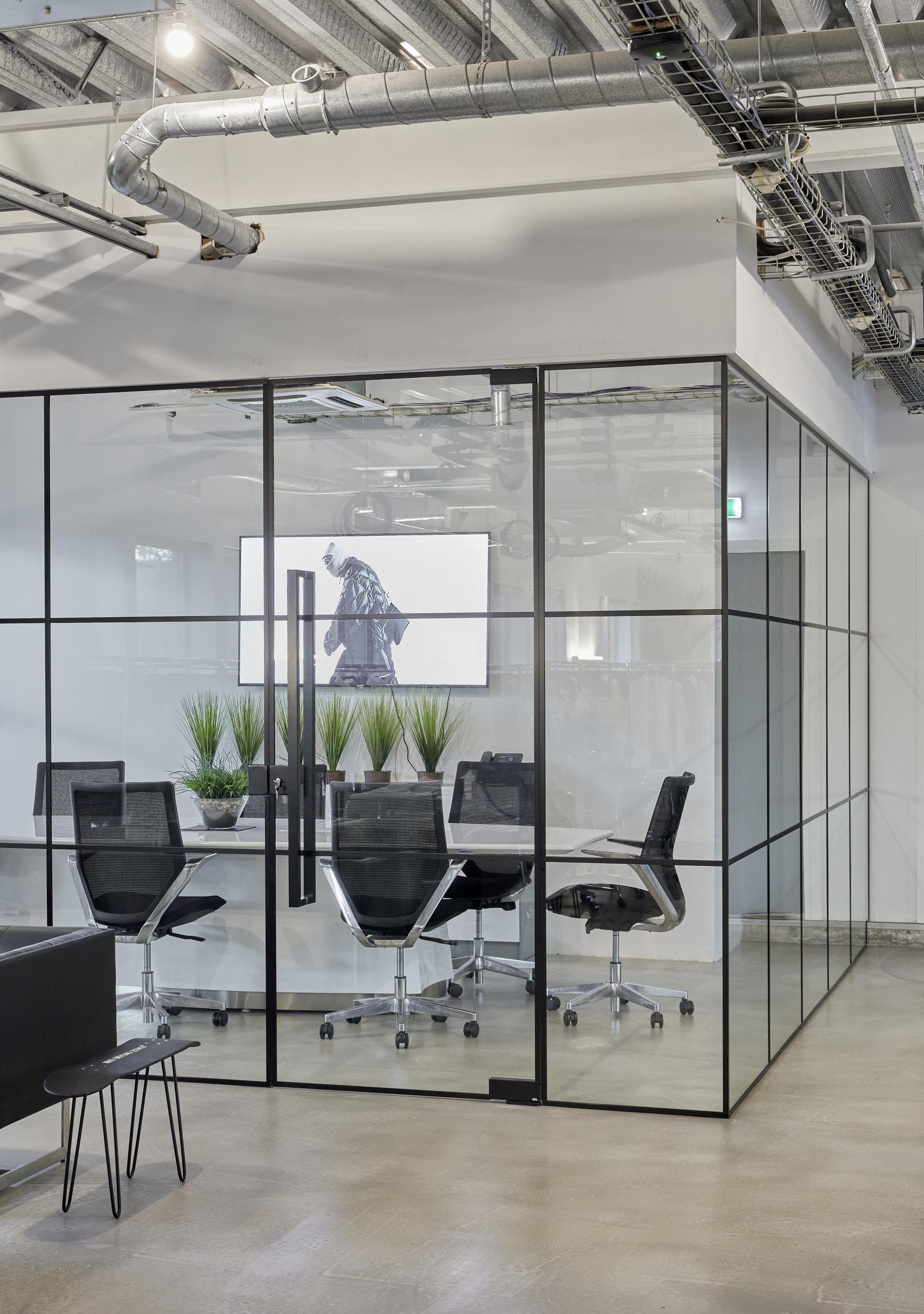 Modern glass meeting room at MKI HQ featuring ergonomic chairs, greenery, and a minimalist design for enhanced wellbeing.