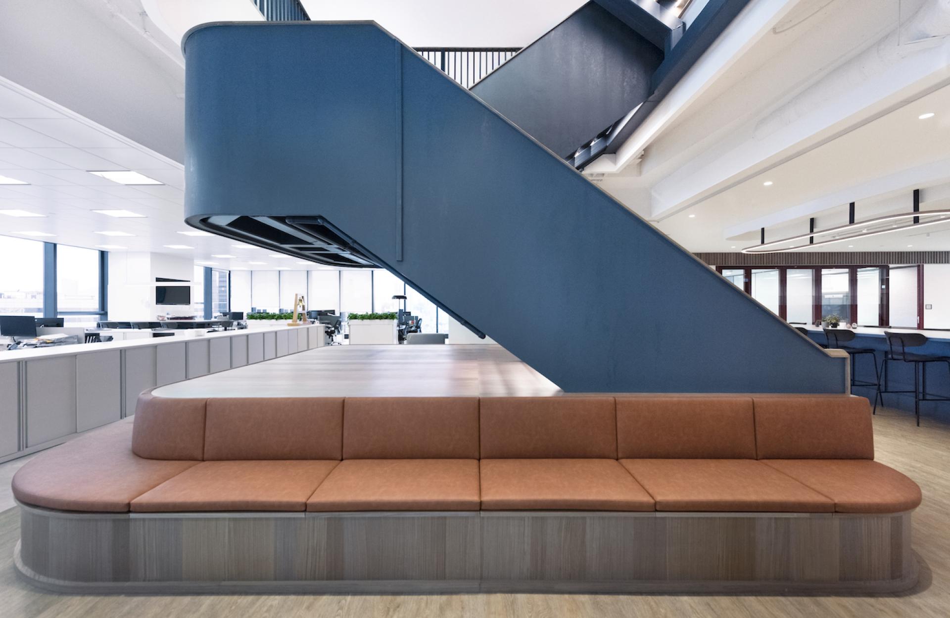 Modern office interior featuring an elegant staircase, plush seating, and open workspace designed by Bean Buro.