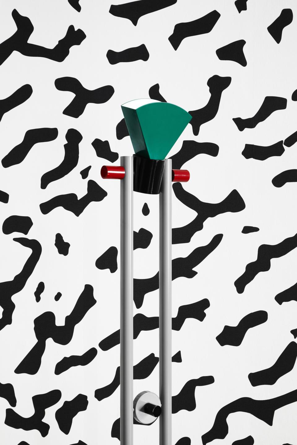 Colorful Memphis Milano design object stands against a bold black-and-white patterned backdrop, highlighting contemporary art influences.