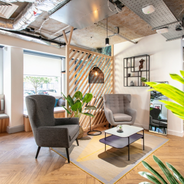 Stylish office space featuring modern seating, decorative plants, and a warm atmosphere, reflecting 2021 design trends.