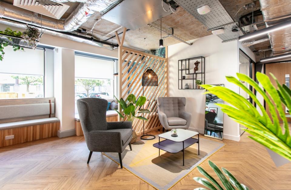 Stylish office space featuring modern seating, decorative plants, and a warm atmosphere, reflecting 2021 design trends.