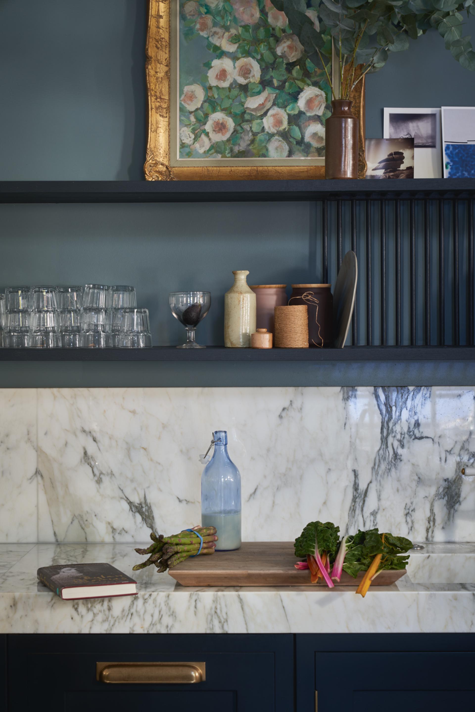 Bold kitchen decor featuring dark blue cabinetry, marble countertop, and fresh vegetables, highlighting Farrow & Ball's vibrant colour palette.