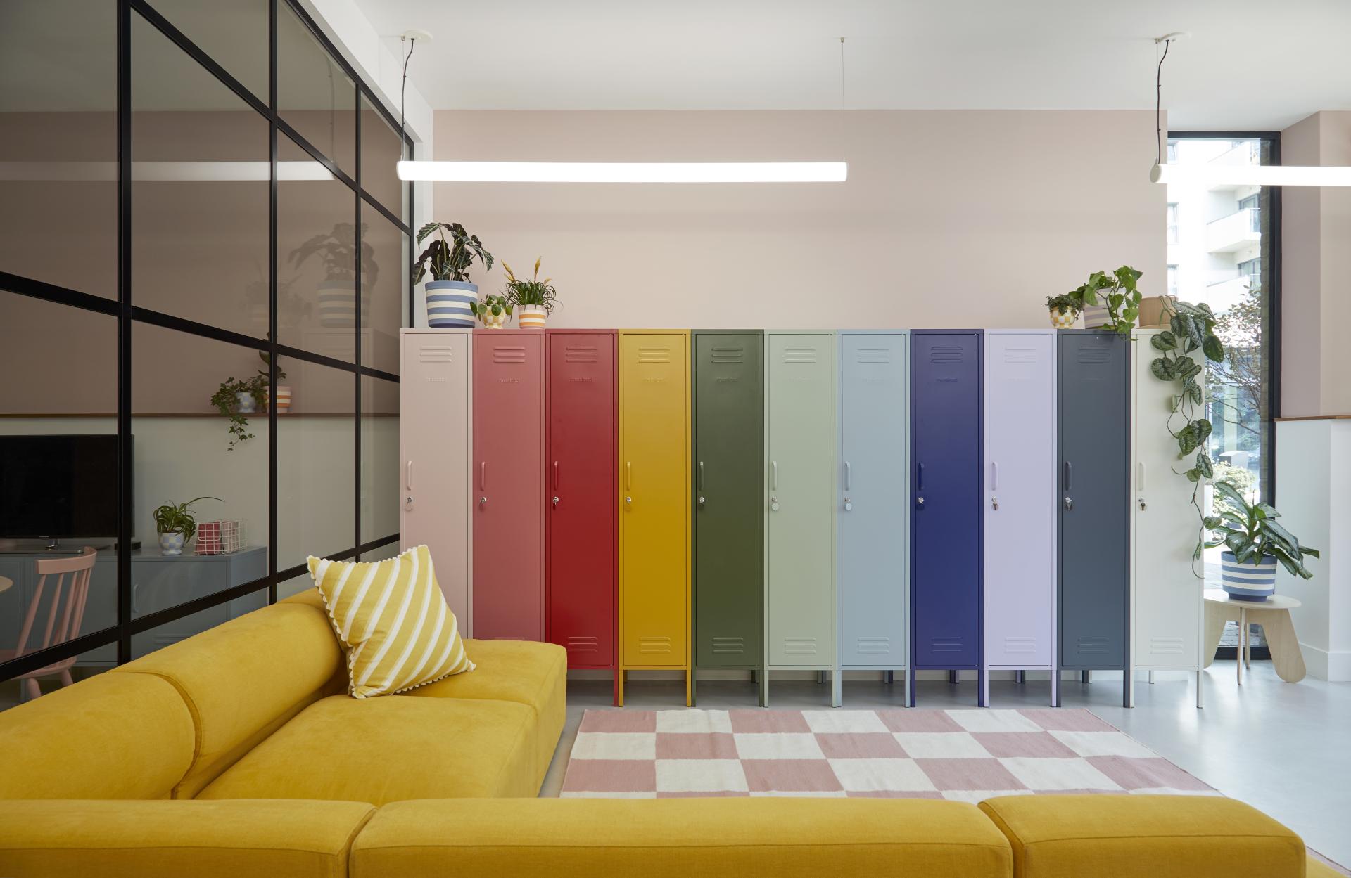 Vibrant office interior featuring colorful lockers, a mustard sofa, and decorative plants, showcasing Mustard Made's creative workspace design.
