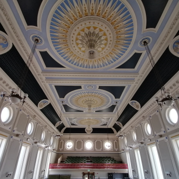 Refurbished ballroom ceiling of Todmorden Town Hall featuring intricate moldings, decorative patterns, and elegant lighting.