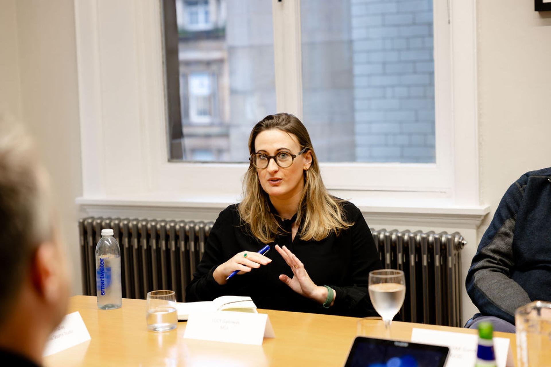 Discussion on Glasgow's property outlook underway, featuring a speaker engaged in conversation during a seminar meeting.