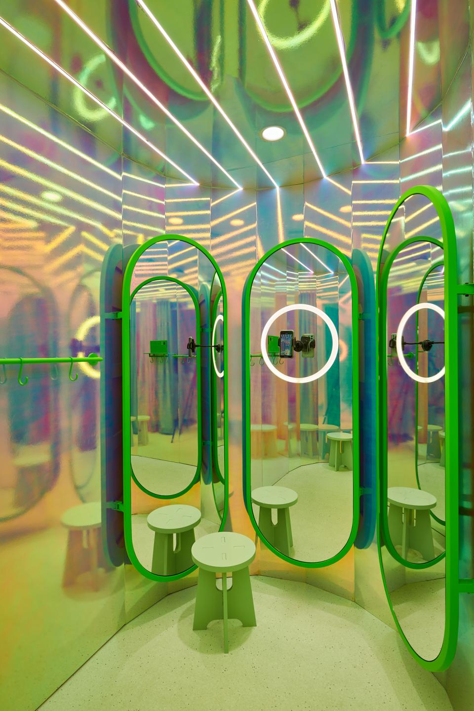 Citrus-themed fitting room design featuring colorful mirrors, green accents, and modern seating at Mango Teen store in Barcelona.