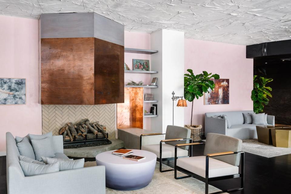 Modern hotel lobby featuring pale pink walls, natural surfaces, and stylish furniture designed by Sean Knibb in Austin.