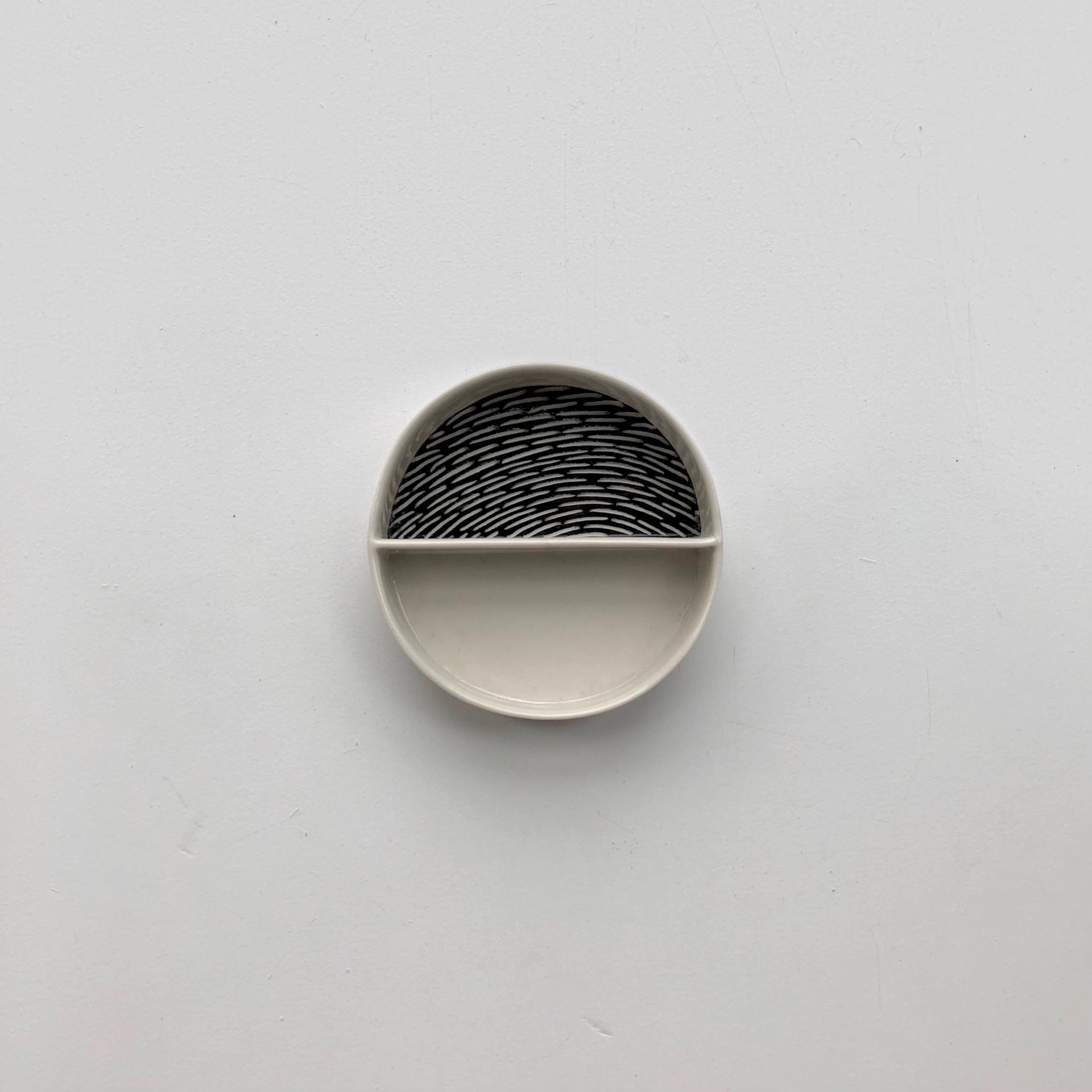 Ceramic dish by Sophie Farrar featuring a divided design with intricate black and white patterns, perfect for showcasing artistry.