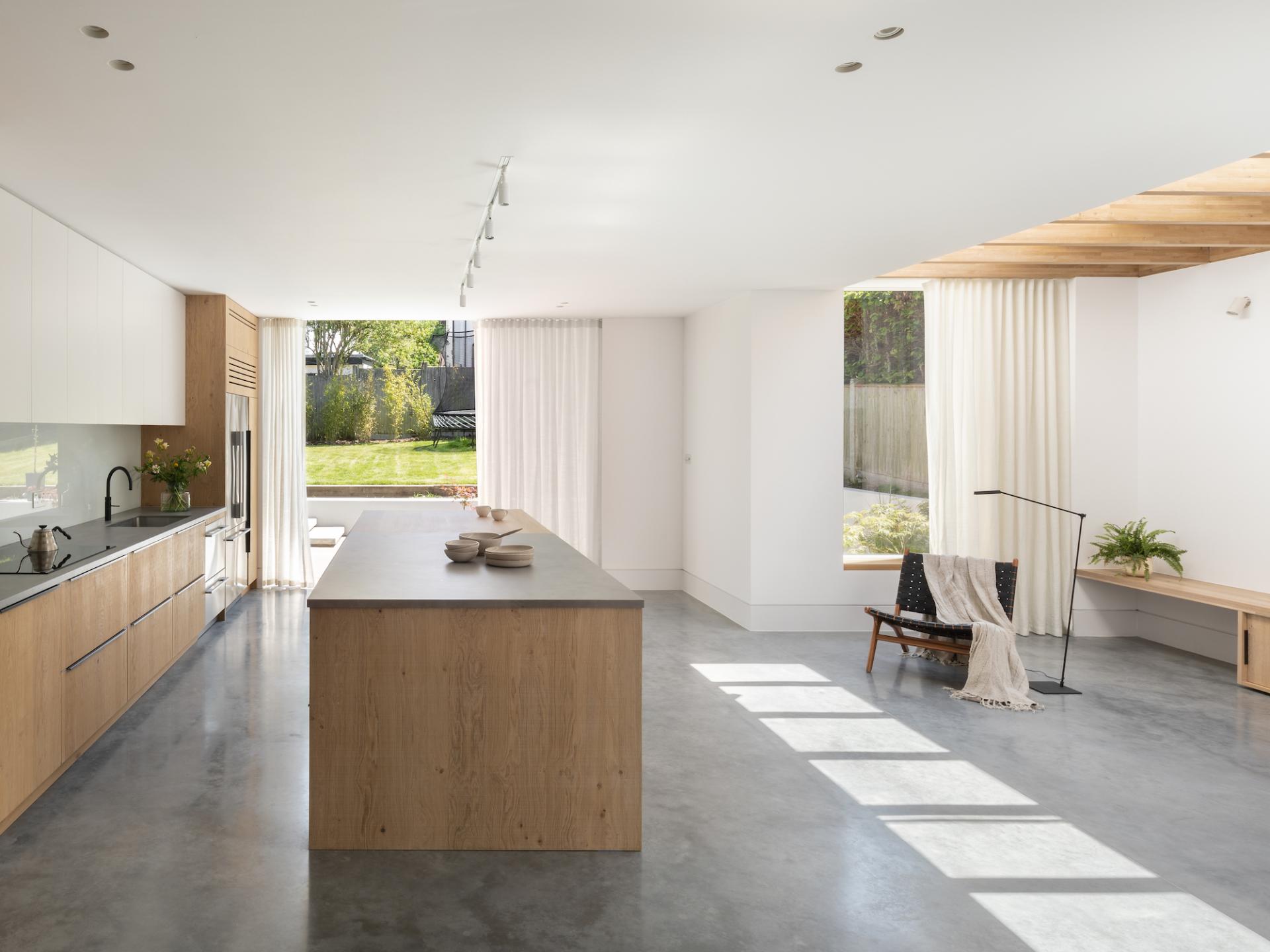 Modern kitchen design in a serene home, showcasing natural light, wood accents, and a connection to the lush outdoor space.