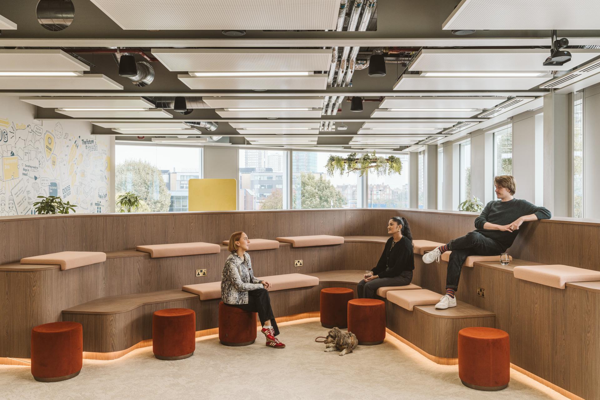 Modern workspace at Butternut Box featuring employees and a dog, emphasizing a pet-friendly environment.