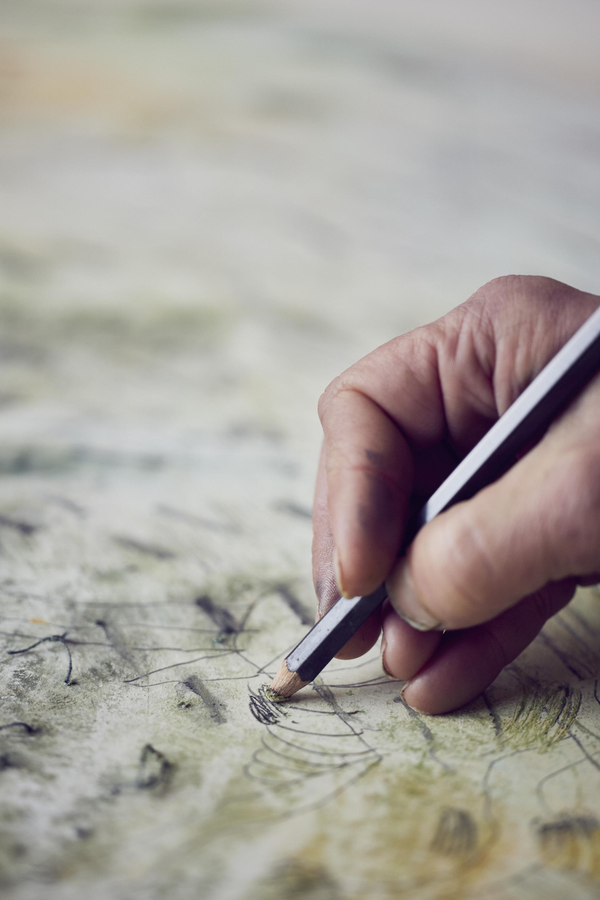 Detail of a hand drawing intricate designs on textured fabric, showcasing the artistry of Manchester textile artist Alice Kettle.