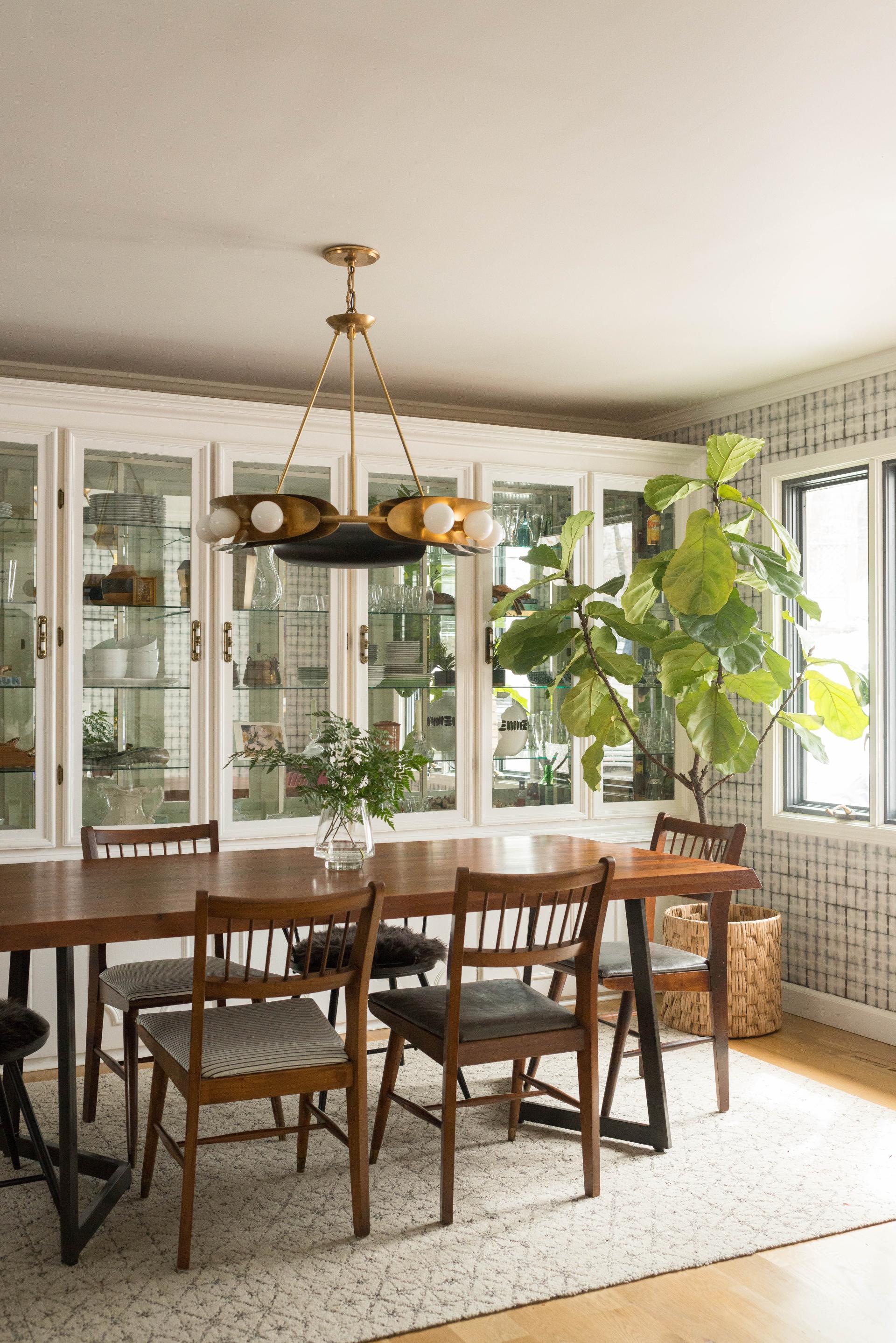 Modern chandelier by Hudson Valley Lighting Group hangs above a wooden dining table in an elegant, contemporary dining room.
