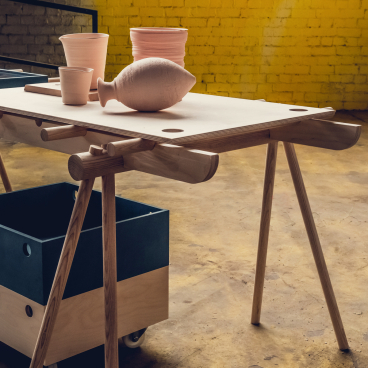 Flexible wooden table featuring clay pottery and storage box, designed for pop-up shops and installations by Tim Denton.
