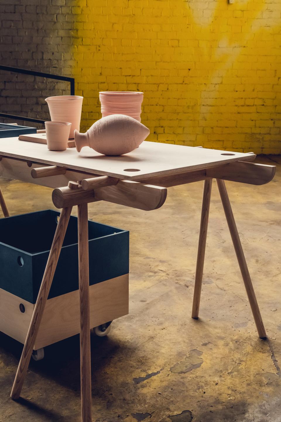 Flexible wooden table featuring clay pottery and storage box, designed for pop-up shops and installations by Tim Denton.