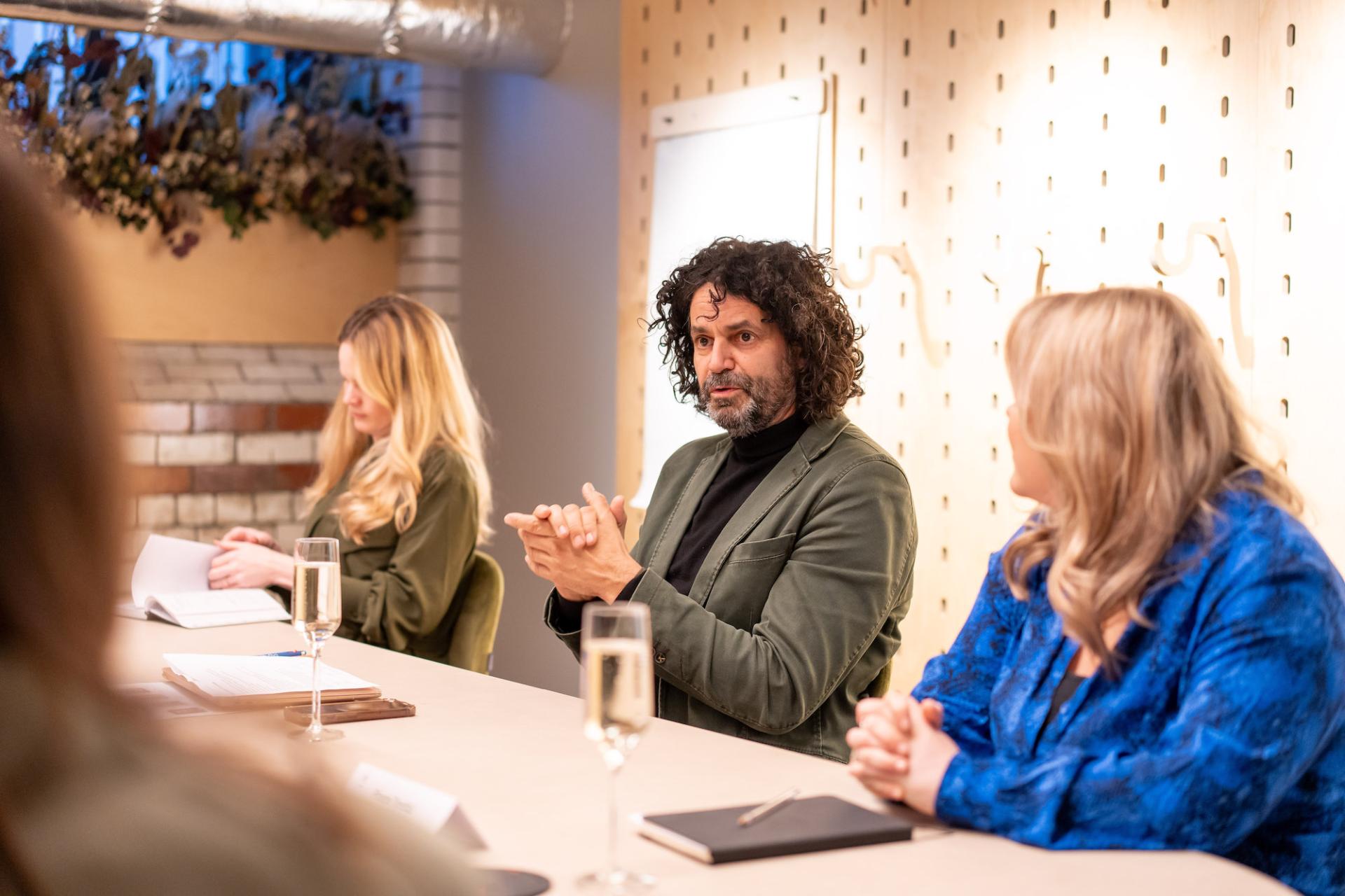 Participants engaged in a roundtable discussion on sustainability and value engineering in a modern meeting space.