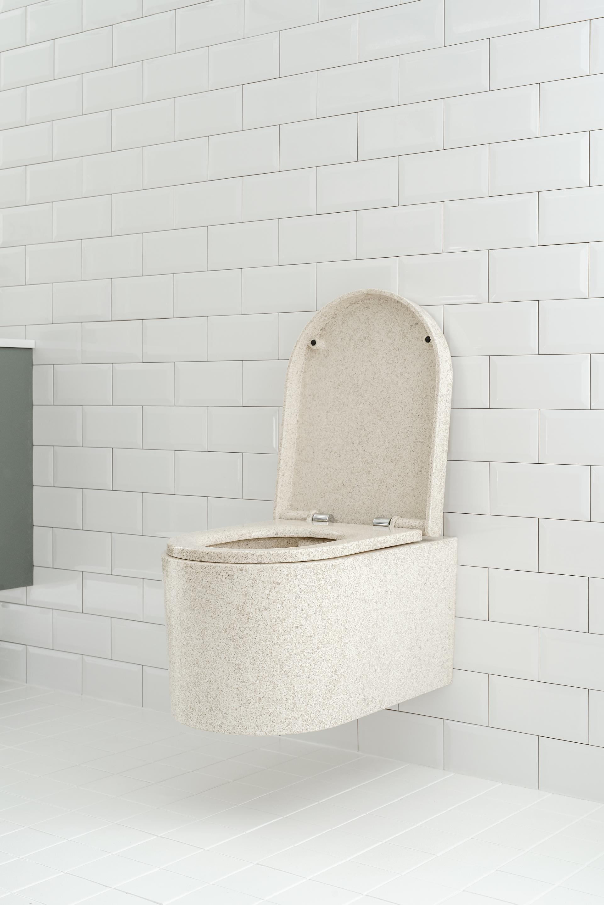 Sleek, 100% waterproof wood composite toilet mounted on a white tiled wall, emphasizing style and sustainability in washroom design.