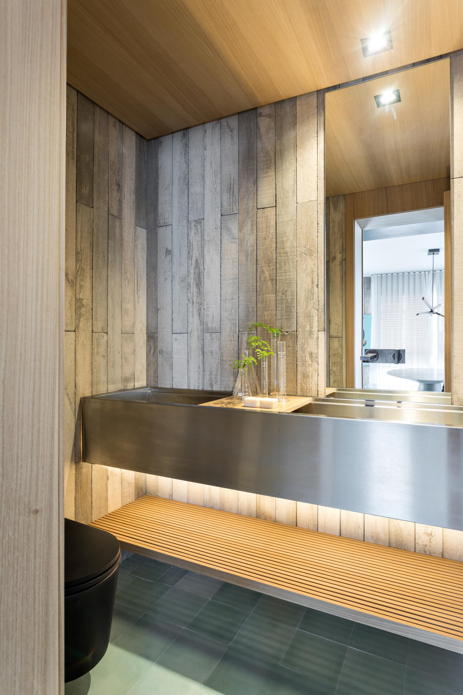 Modern bathroom design featuring a sleek metal vanity, wooden accents, and stylish decor in São Paulo apartment.