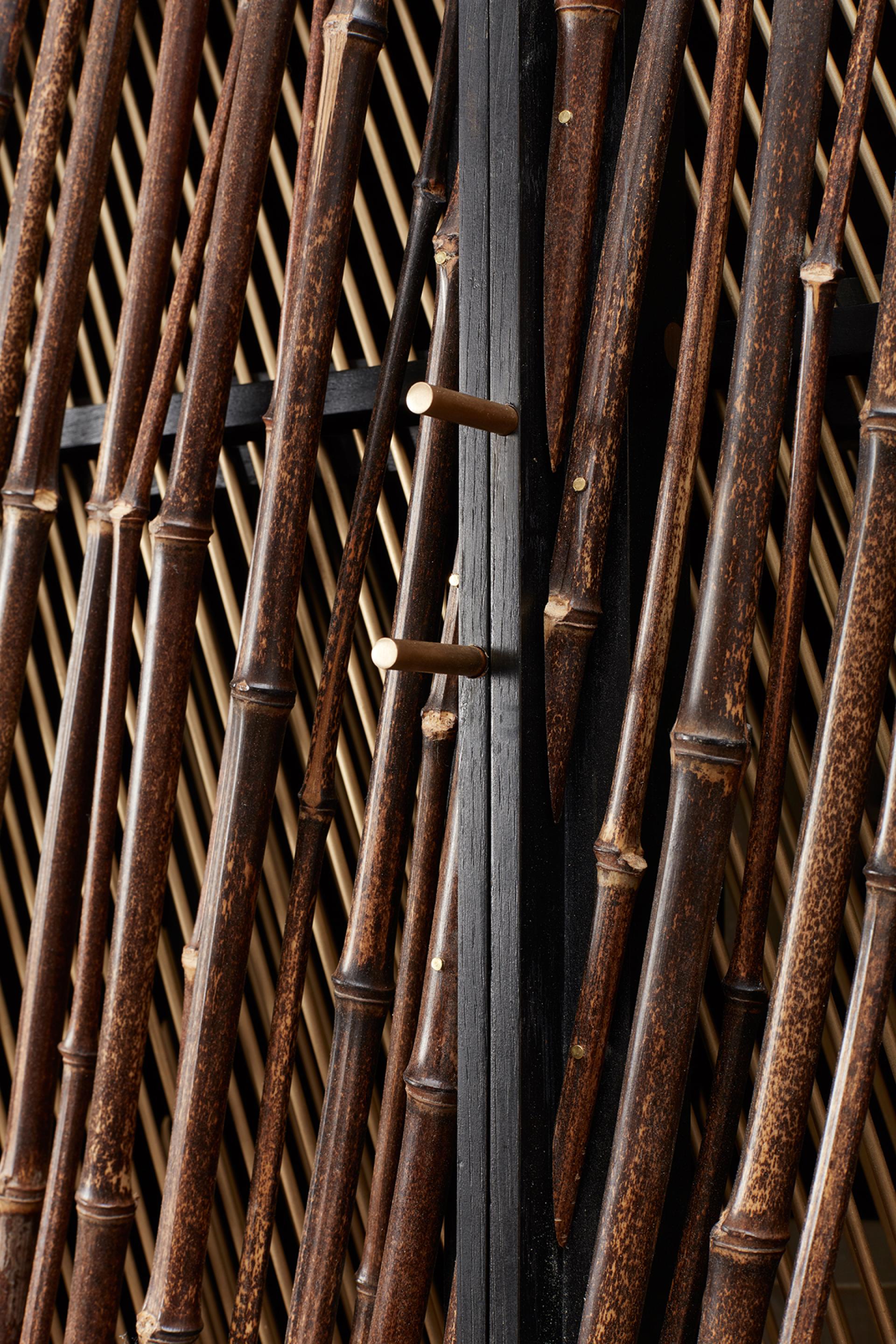 Japanese-inspired black stained drinks cabinet featuring bamboo-like wooden slats and elegant brass accents by Hugh Miller Furniture.