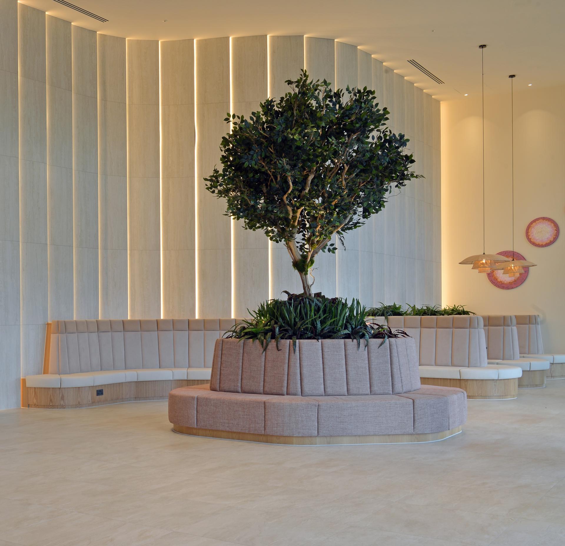 Modern workspace featuring a central tree planter surrounded by stylish seating and ambient lighting, emphasizing innovative design in architecture.
