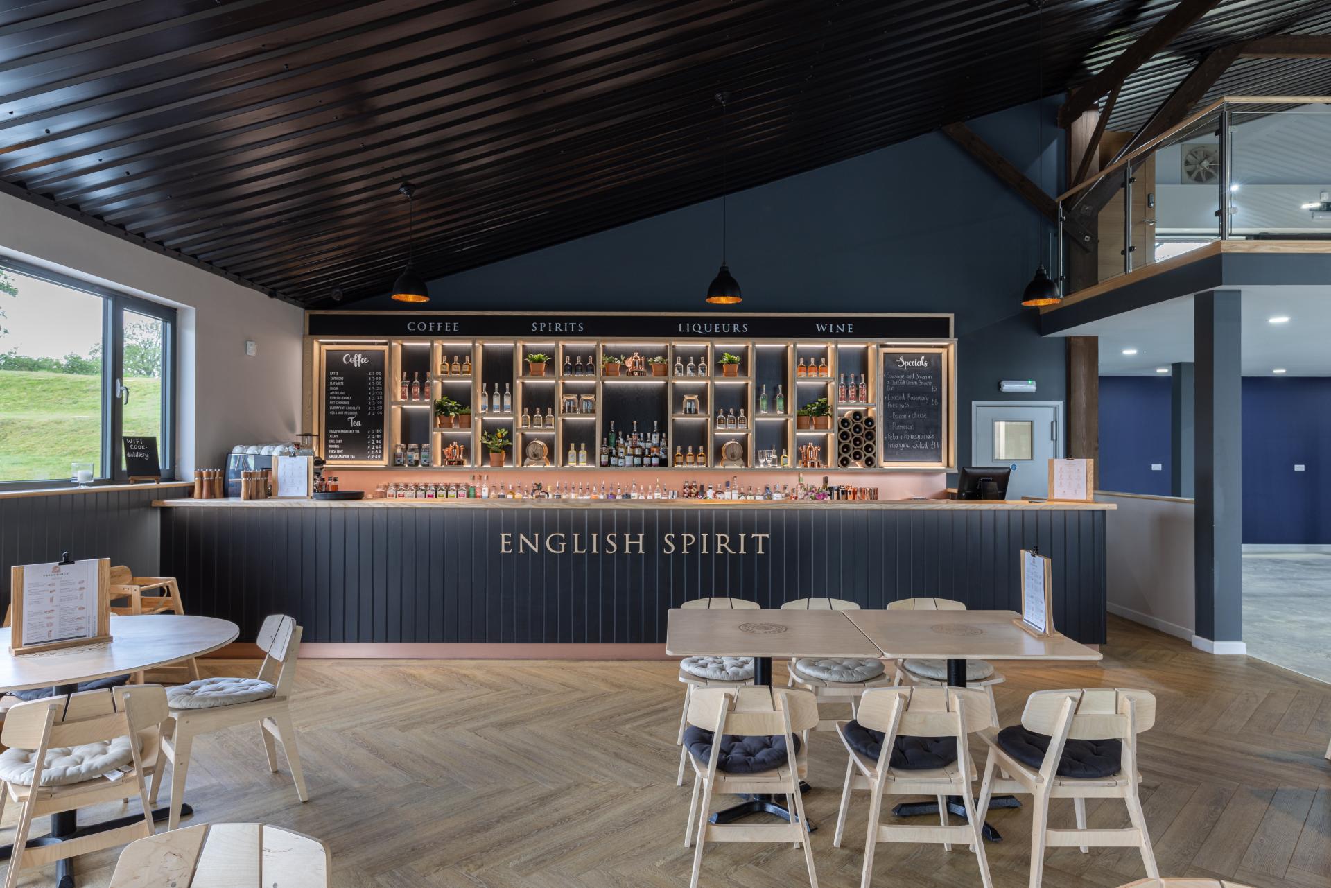 Modern bar interior at The English Spirit Distillery featuring a selection of spirits, liqueurs, and welcoming seating area.